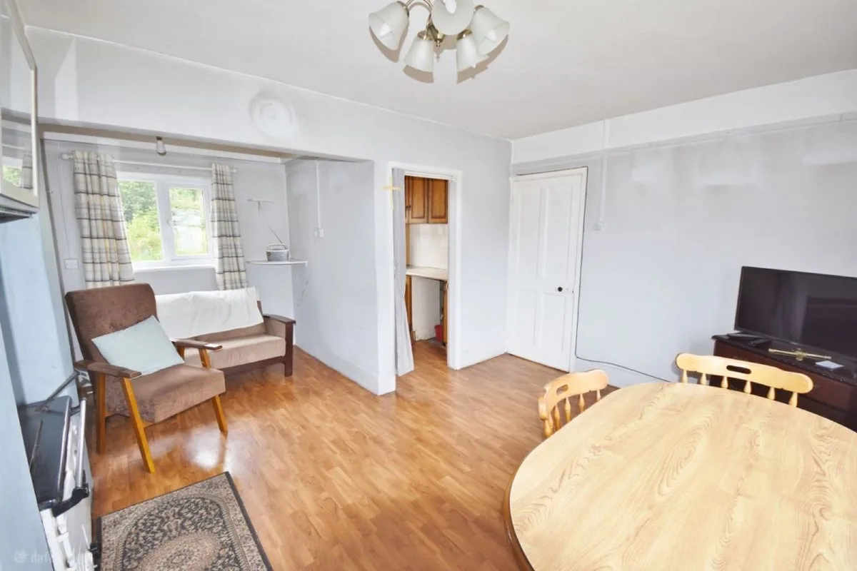 Living and dining room before refurbishment with wood flooring and patterned wallpaper